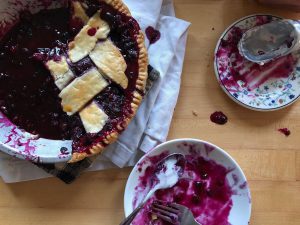 half-eaten blueberry pie with dirty plats