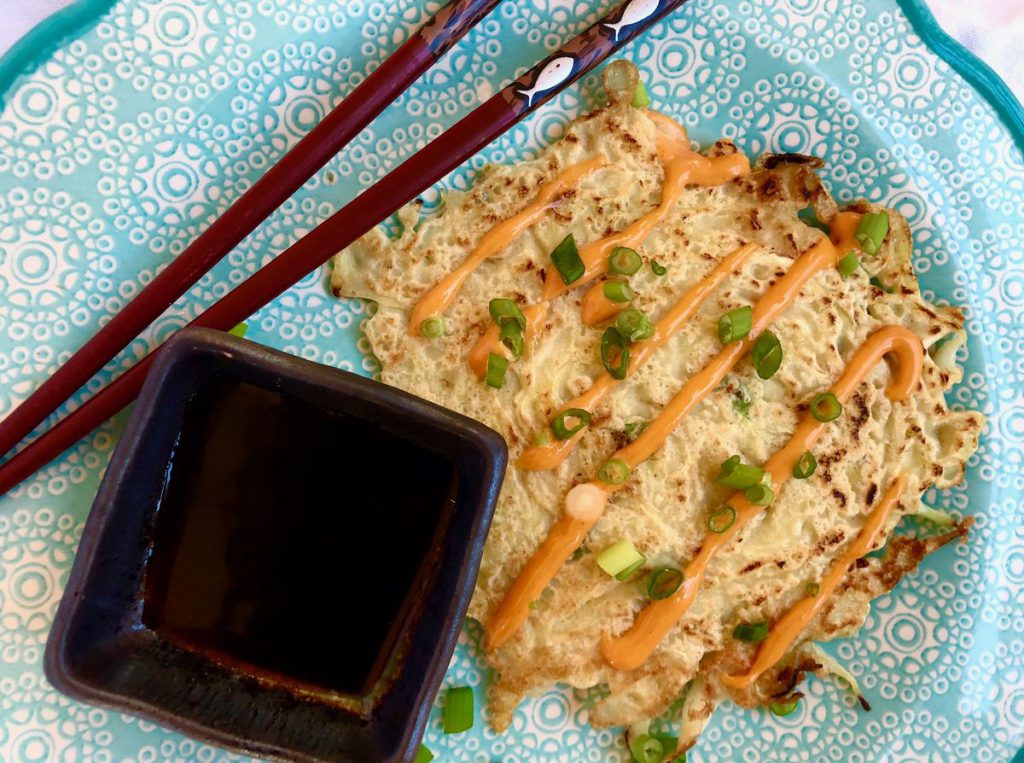 vegetable pancake on a blue plate slashed with sauce