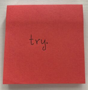 Word "try" written on a red sticky note