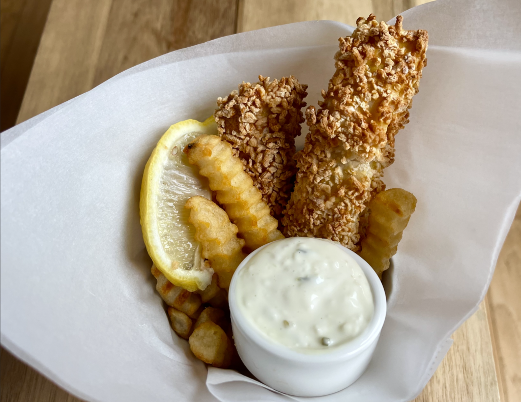 pieces of fish and fries wrapped in paper with tartar sauce