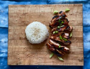 a sliced grilled chicken thigh and a scoop of rice