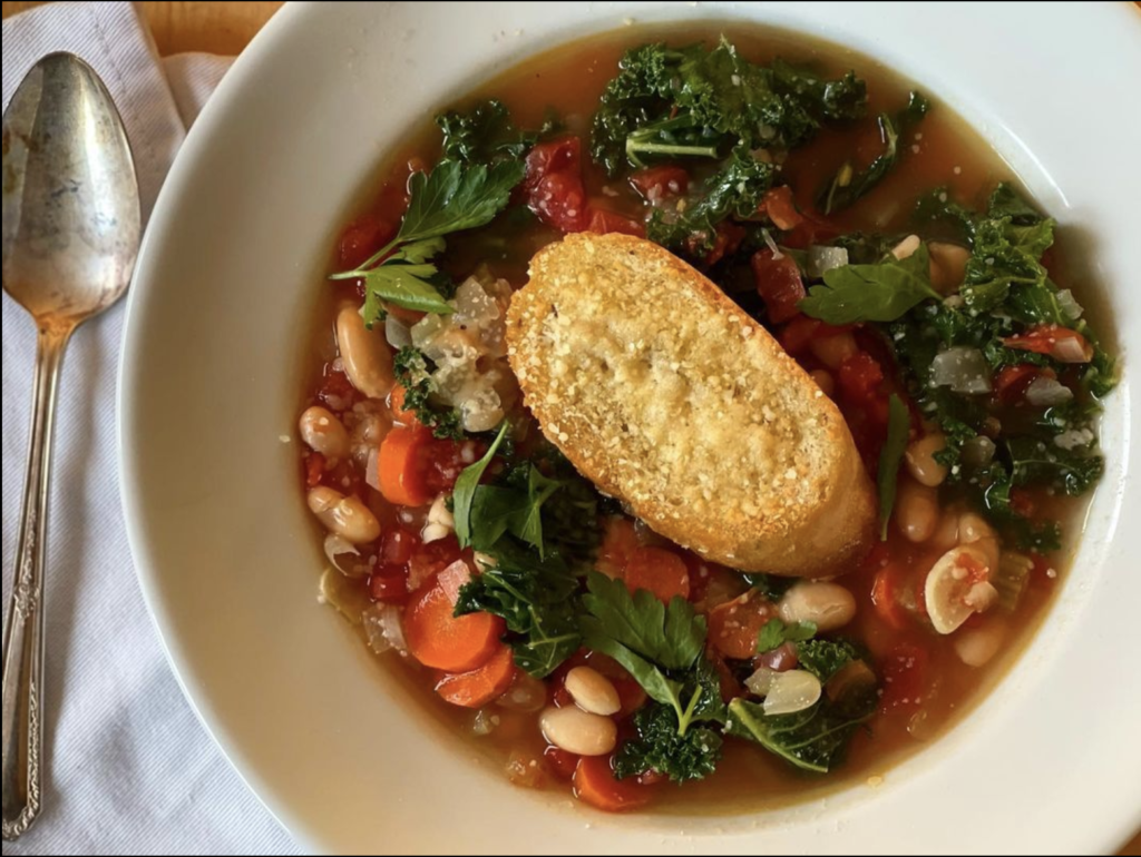 bowl of vegetable soup with a piece of toasted bread on top