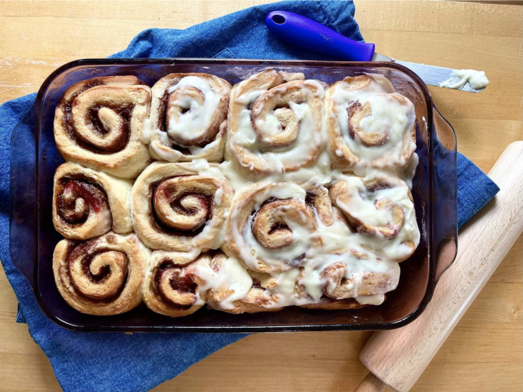 berry cinnamon rolls, partially frosted, on a blue cloth