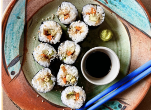 sushi rolls on a plate with a small bowl of soy sauce and chopsticks