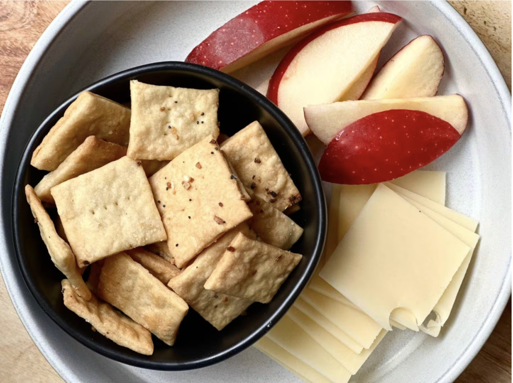 bowl of crackers, apples, swiss cheese