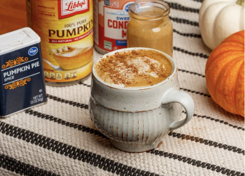 Mug with foamy coffee in it with spicy can and canned pumpkin in the background