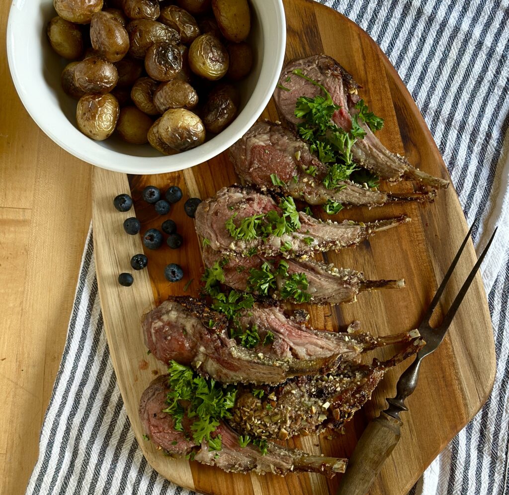 Cuts of lamb on a cutting board with roasted potatoes
